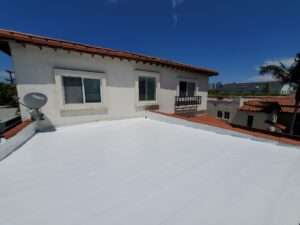 White silicone flat roof coating on Spanish-style home terrace by Coronado Roof Care in Los Angeles, CA, License #1127354.
