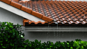 Heavy rain spilling off a tiled roof without gutters, illustrating water runoff during Santa Clarita rainstorms